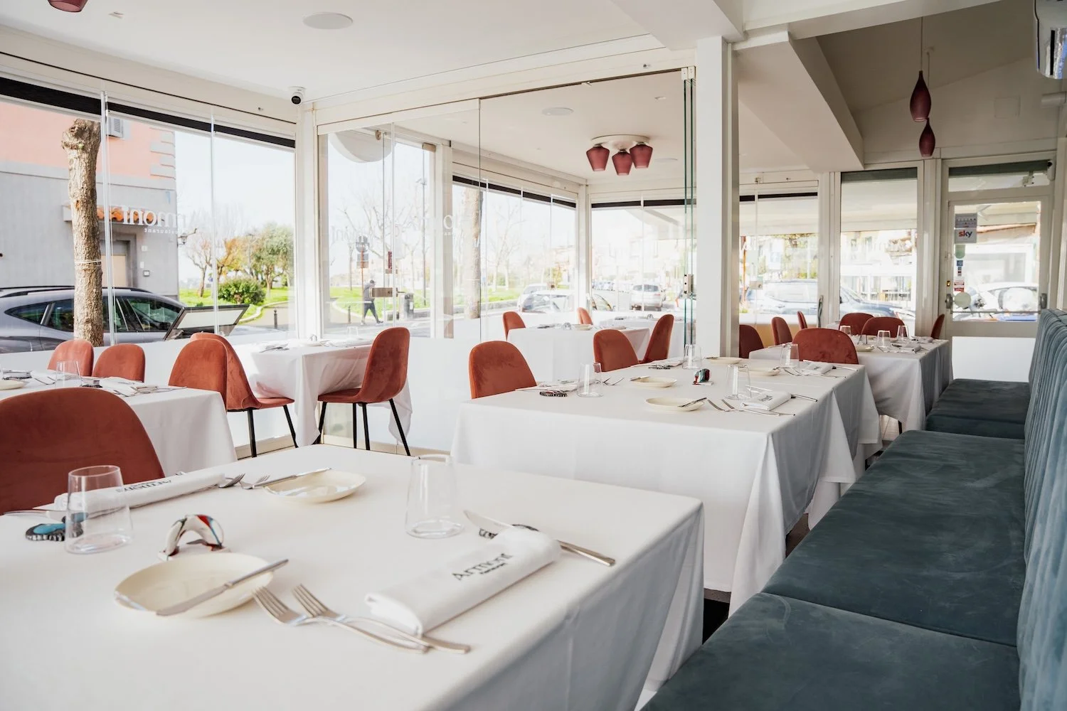 Sala di Armonì Restaurant Pozzuoli con tavoli apparecchiati, sedute rosa e divano blu