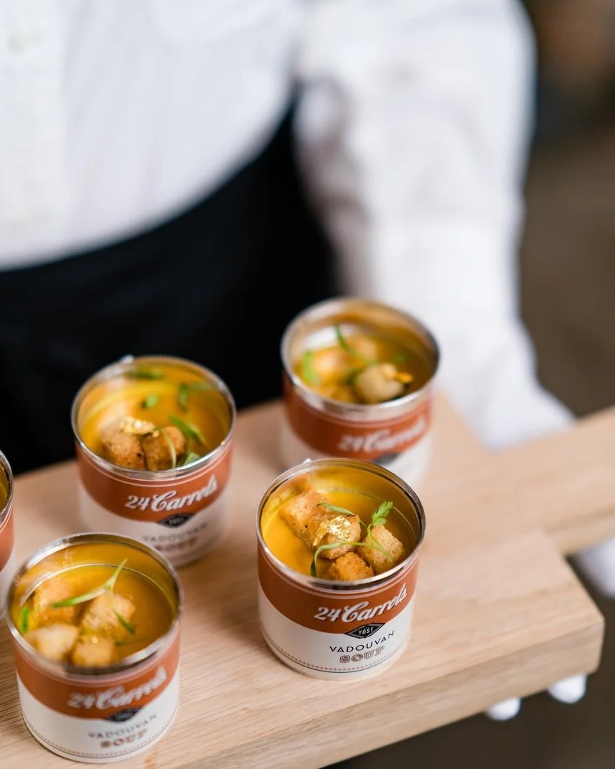 Four small cups of soup garnished with herbs and croutons on a wooden tray.