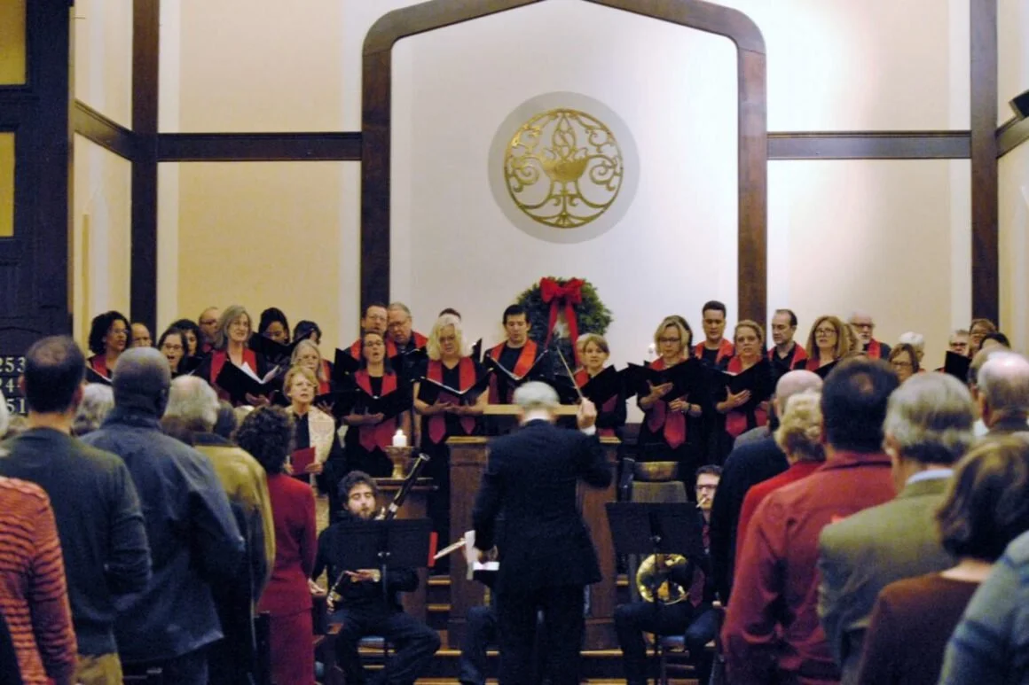 A choir performing in a church or concert hall with a conductor leading and an audience watching.