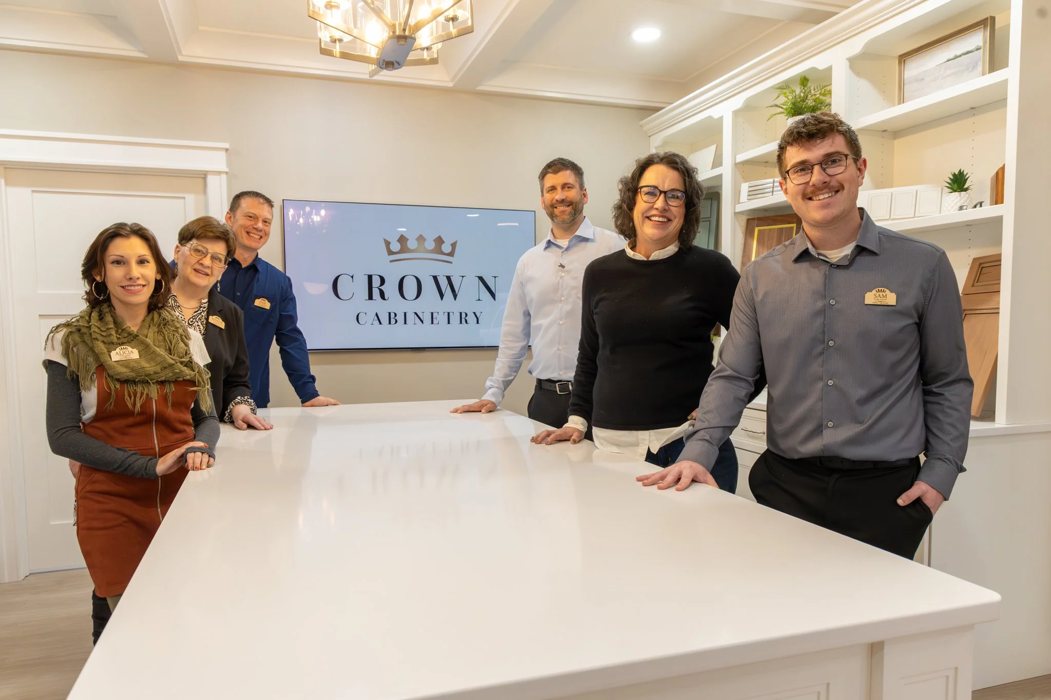 The Crown Cabinetry professional design and sales team standing together in their modern kitchen showroom in Chetek, Wisconsin.