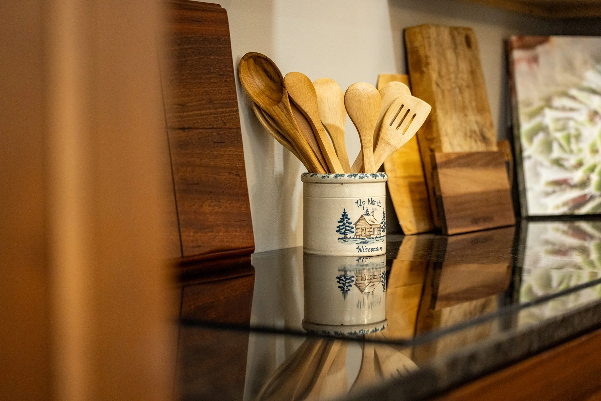 Handcrafted wooden utensils reflecting on a high-gloss countertop, showcasing the warm wood tones and quality finishes used by Crown Cabinetry.