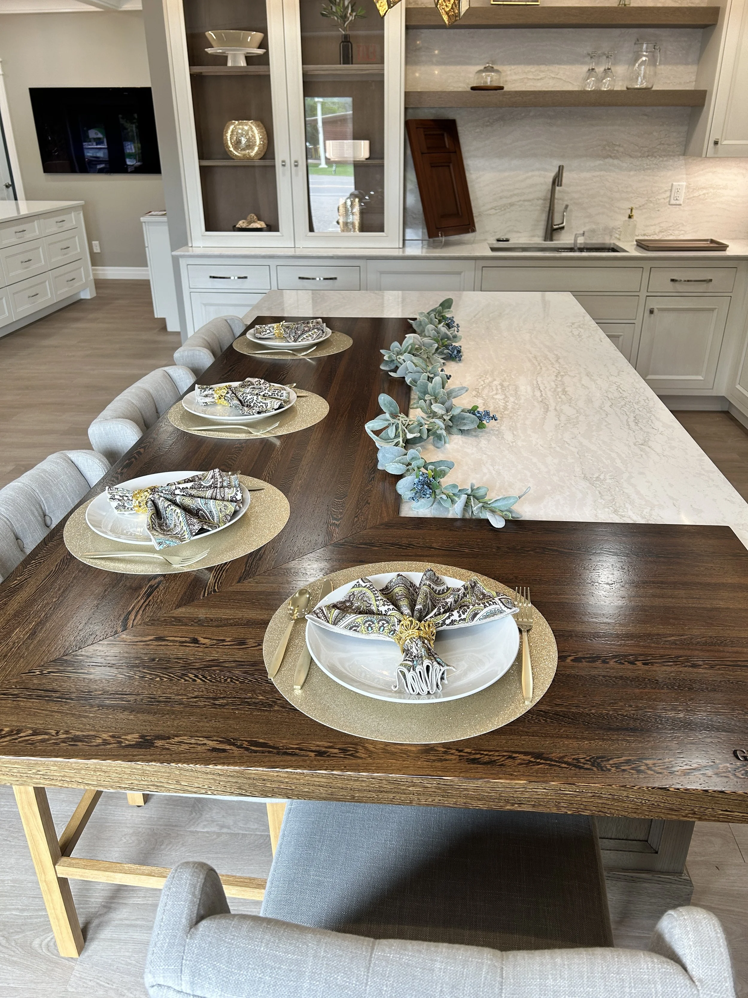 Showroom dining table display with a live-edge style wood top and a white custom kitchen vignette in the background.