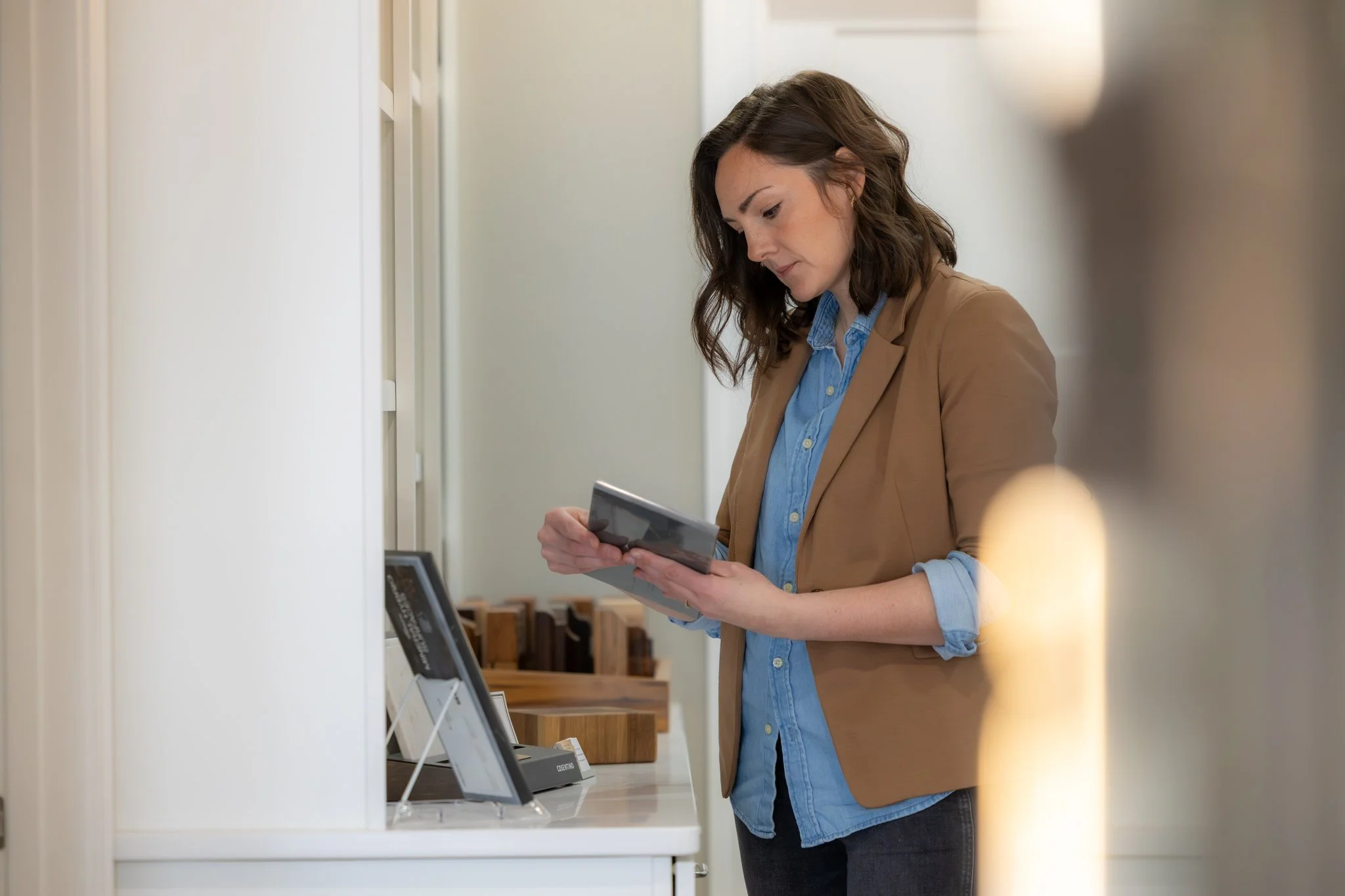 A professional interior designer reviewing custom cabinetry samples and project details on a tablet in a modern showroom.