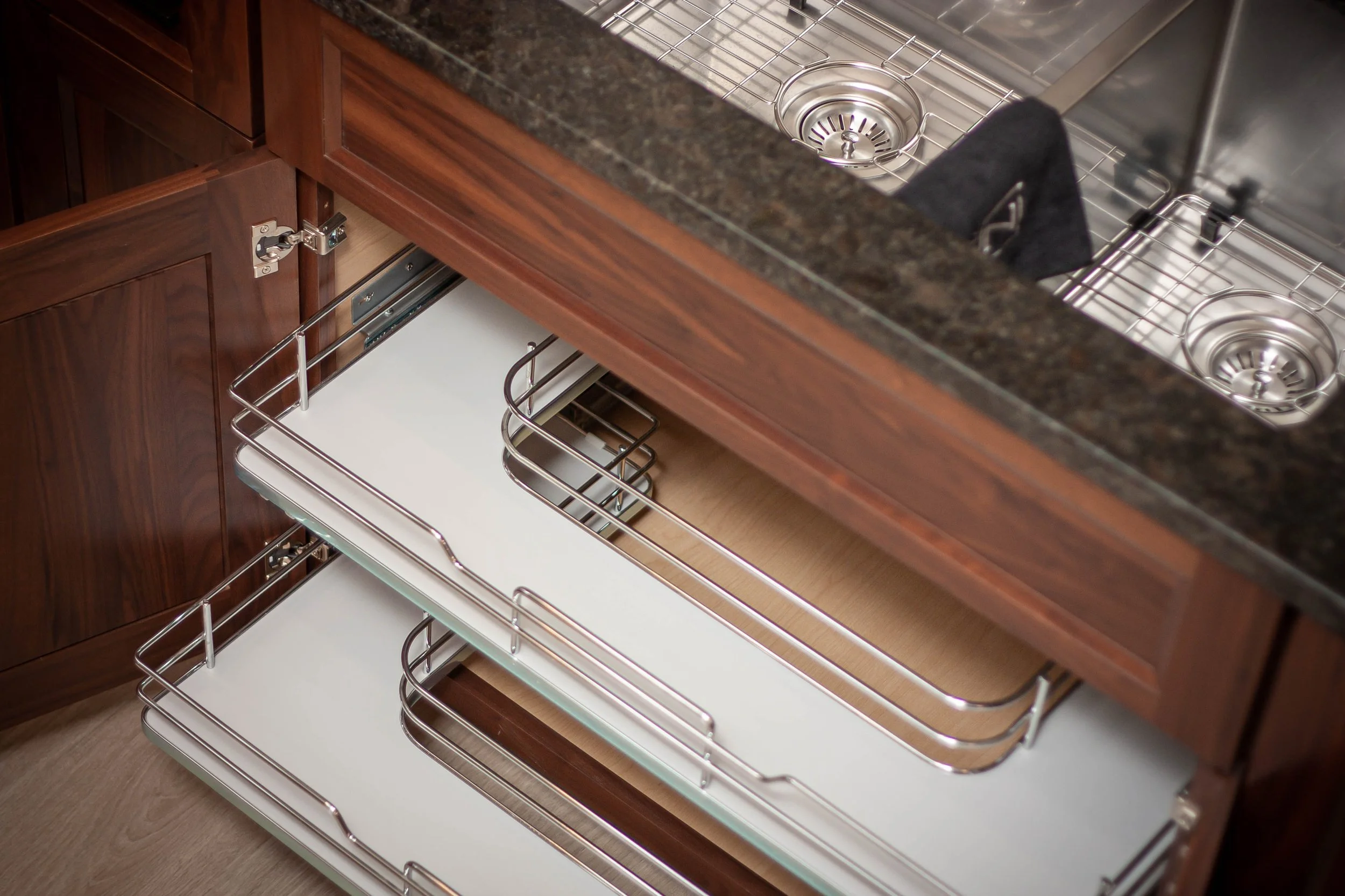 Interior view of a custom kitchen cabinet featuring a smooth pull-out wire storage basket mechanism.