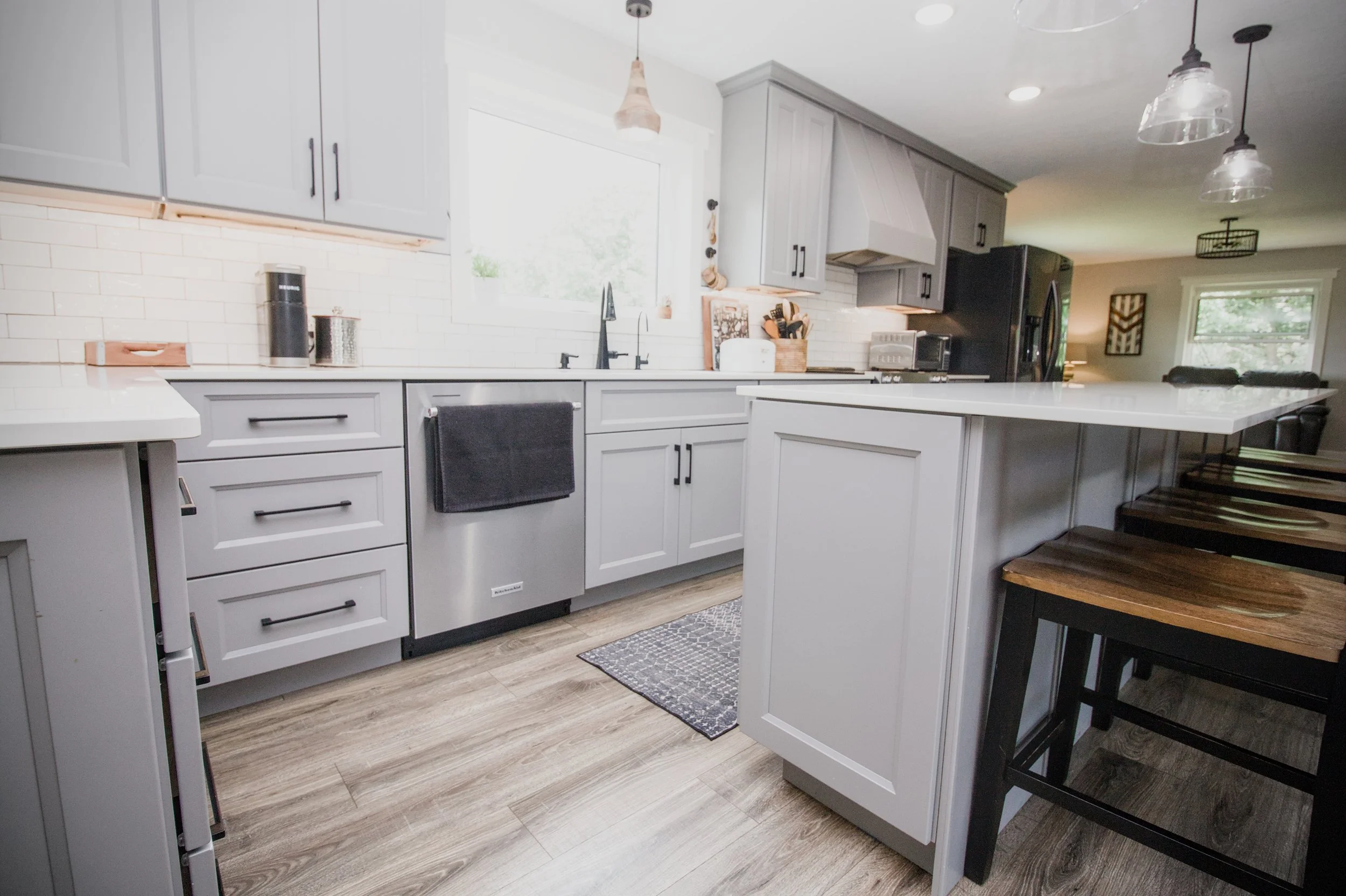 Open-concept kitchen with oak wood cabinets, a contrasting stained island featuring black hardware pulls, white appliances, and a central sink faucet