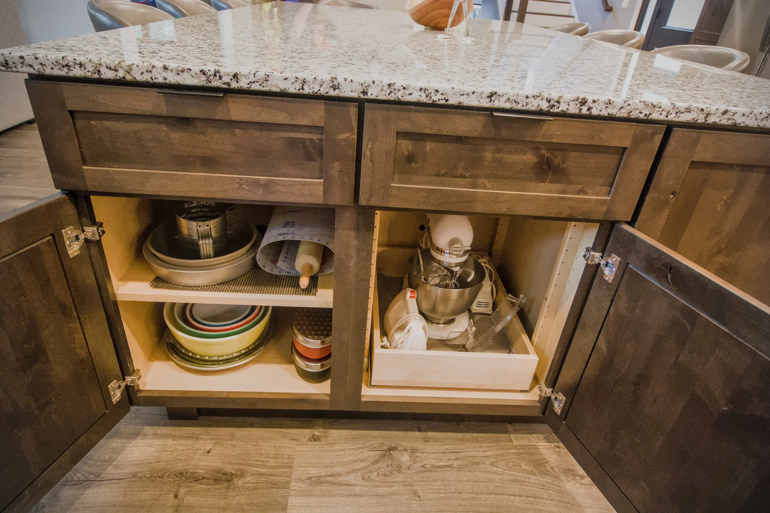 Custom dark charcoal kitchen island with hidden pull-out storage shelves for kitchen organization.