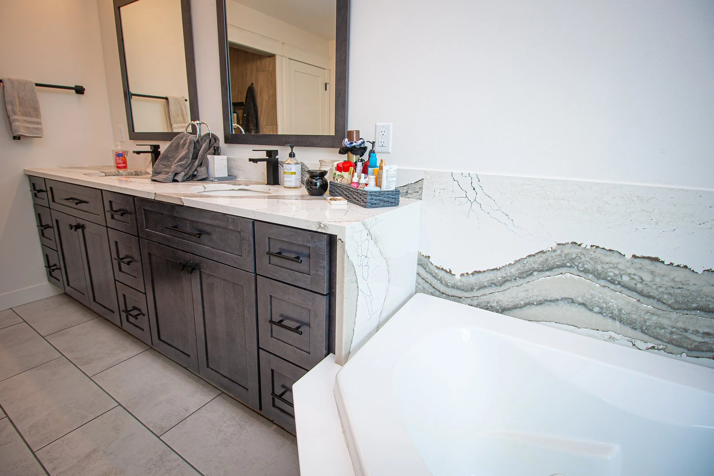 Modern bathroom vanity with dark gray textured cabinetry, matte black hardware pulls, black faucet, and white quartz countertop