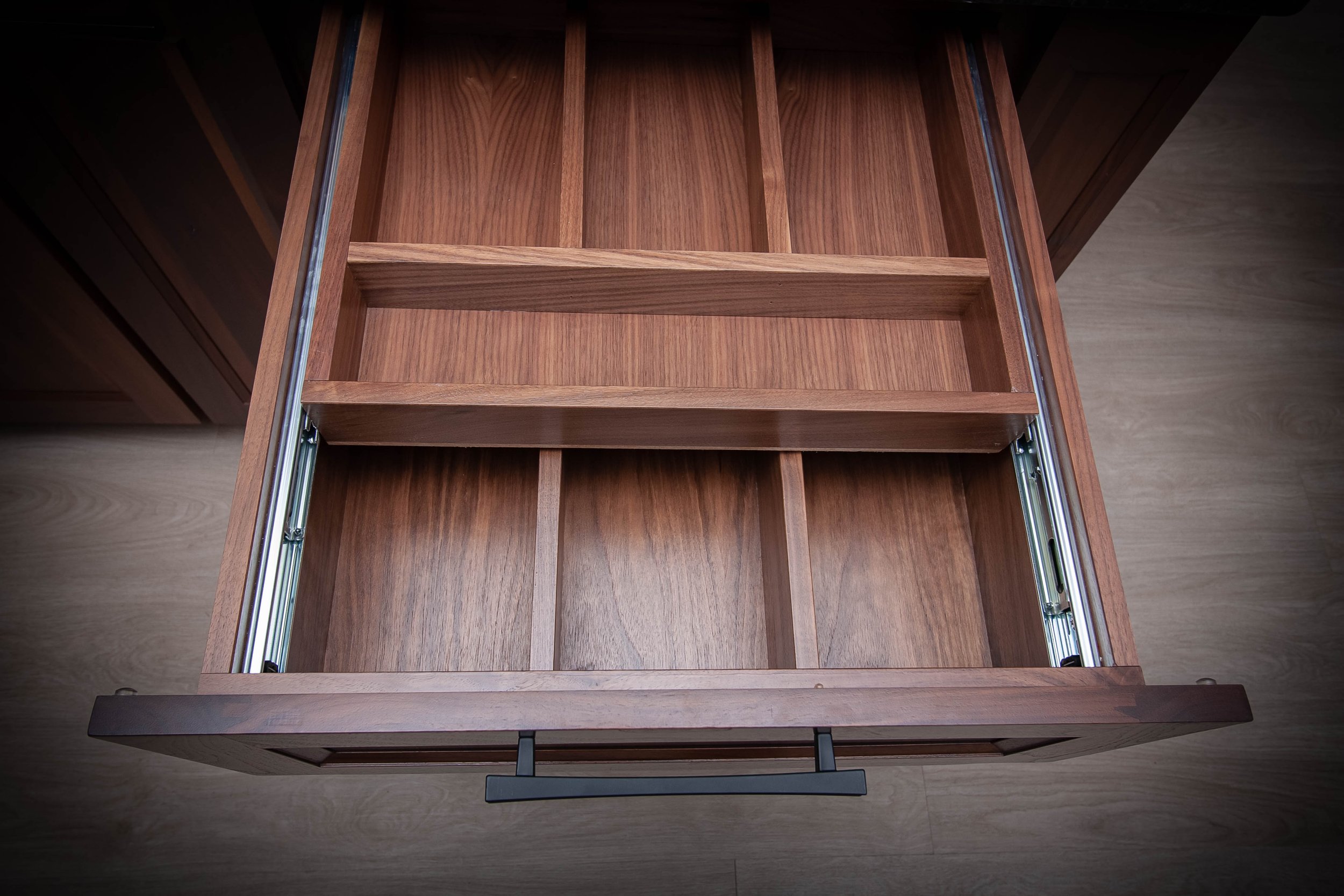 Deep natural wood drawer organization inserts and custom cutlery dividers inside a showroom cabinet display.