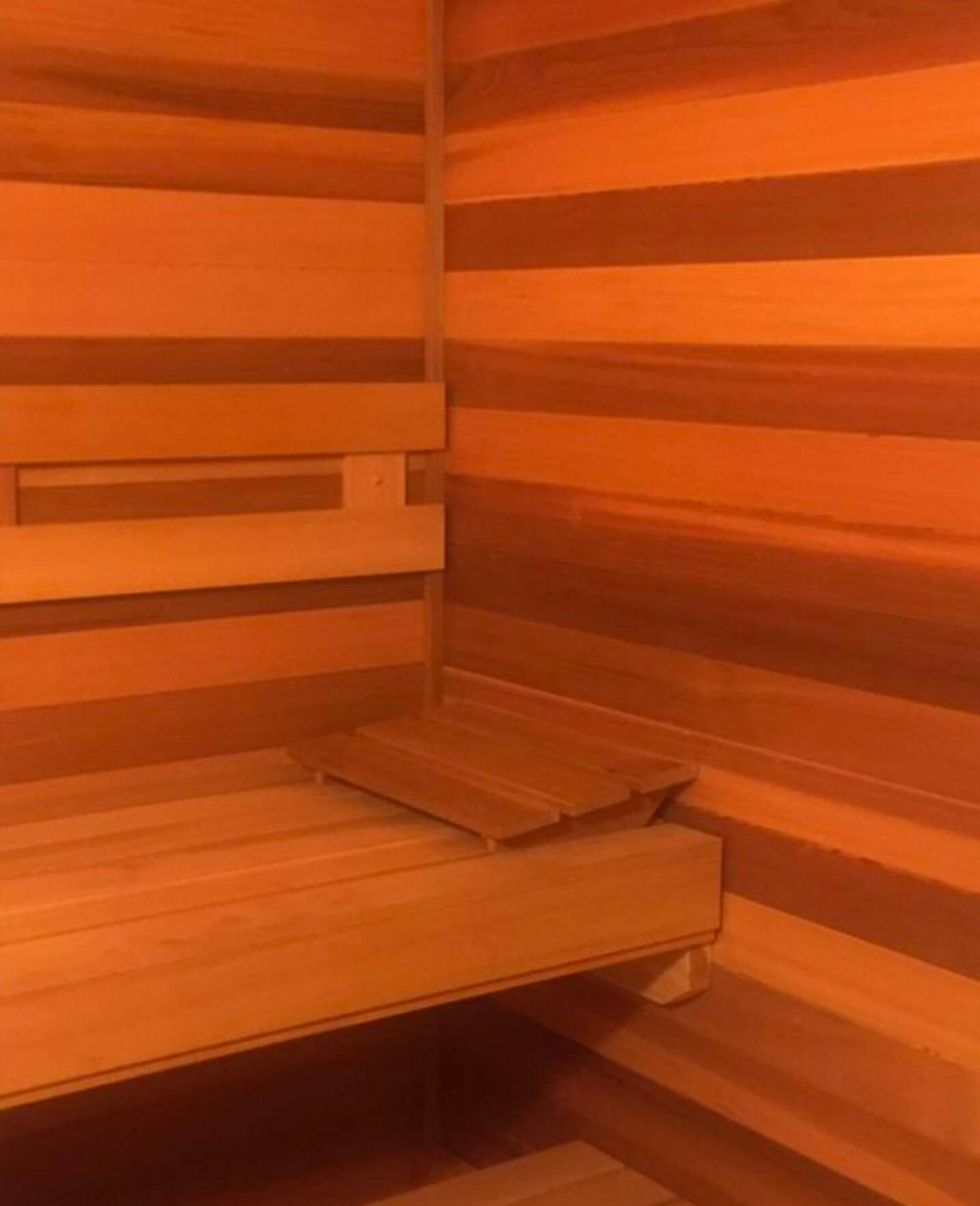 Empty wooden sauna room with benches along the walls and a small wooden platform.