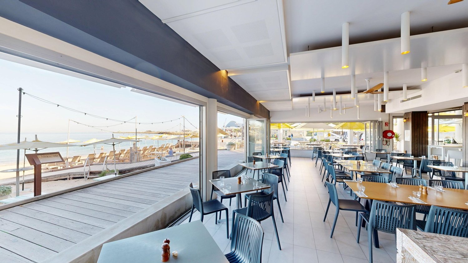 Tables in the Bathers Beach House restaurant, open to the boardwalk and the beach