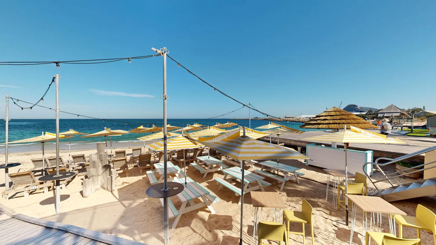 Licensed beach area with tables directly on the sand at Bathers Beach House