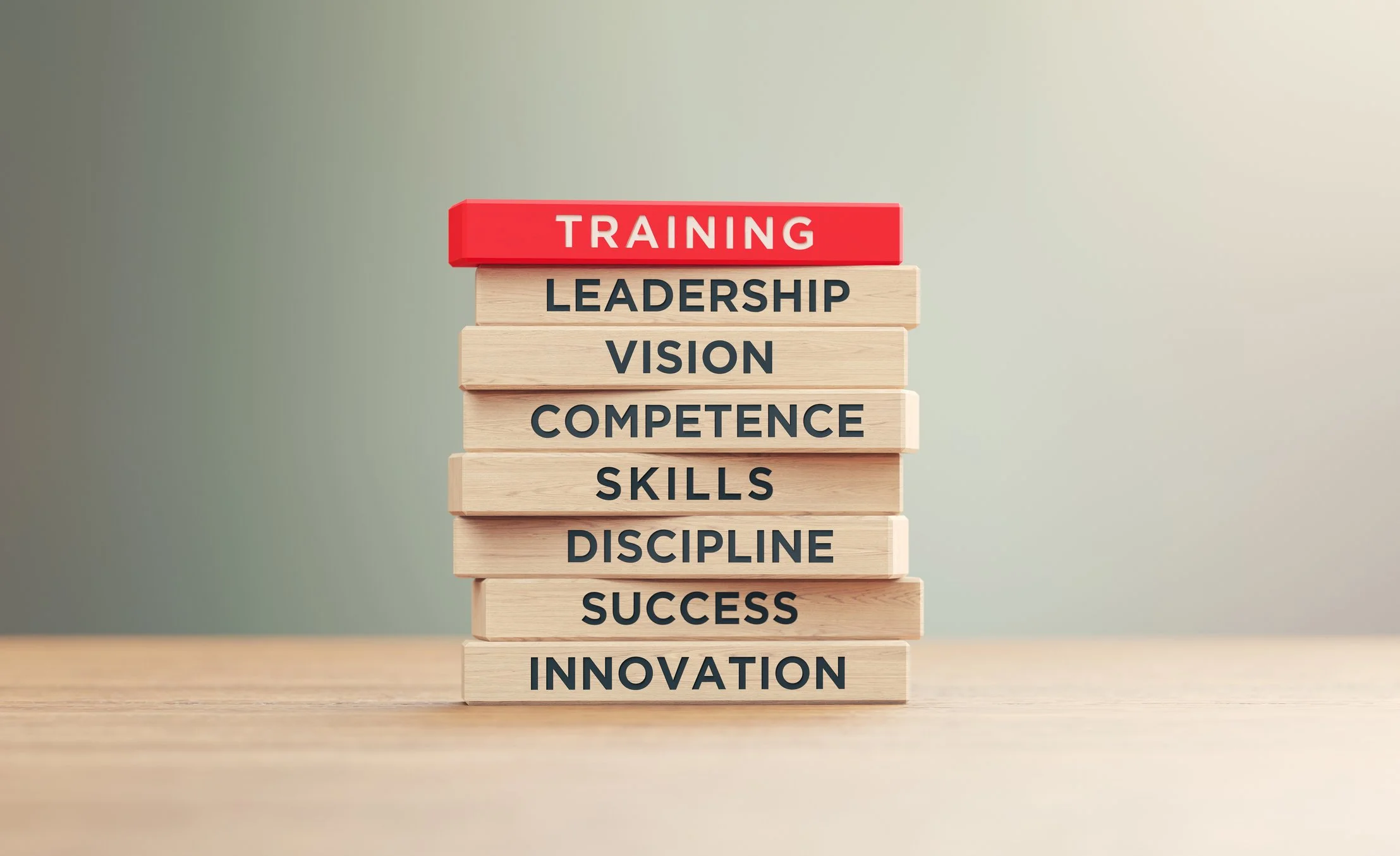 Stacked wooden blocks with words related to personal development, topped with a red block labeled 'Training' on a wooden surface.