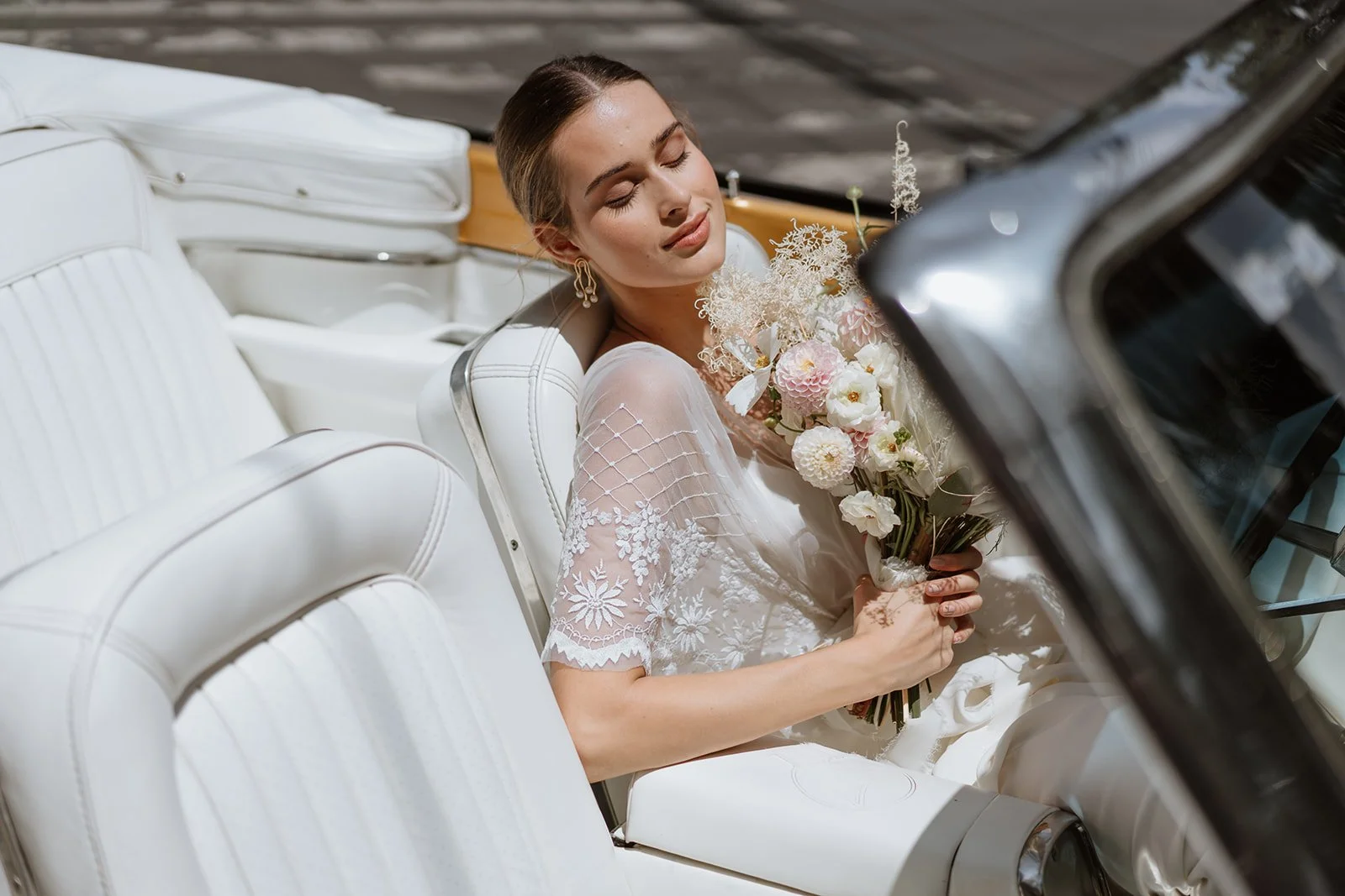 modern bride in vintage car with romantic bouquet and fashion inspired look