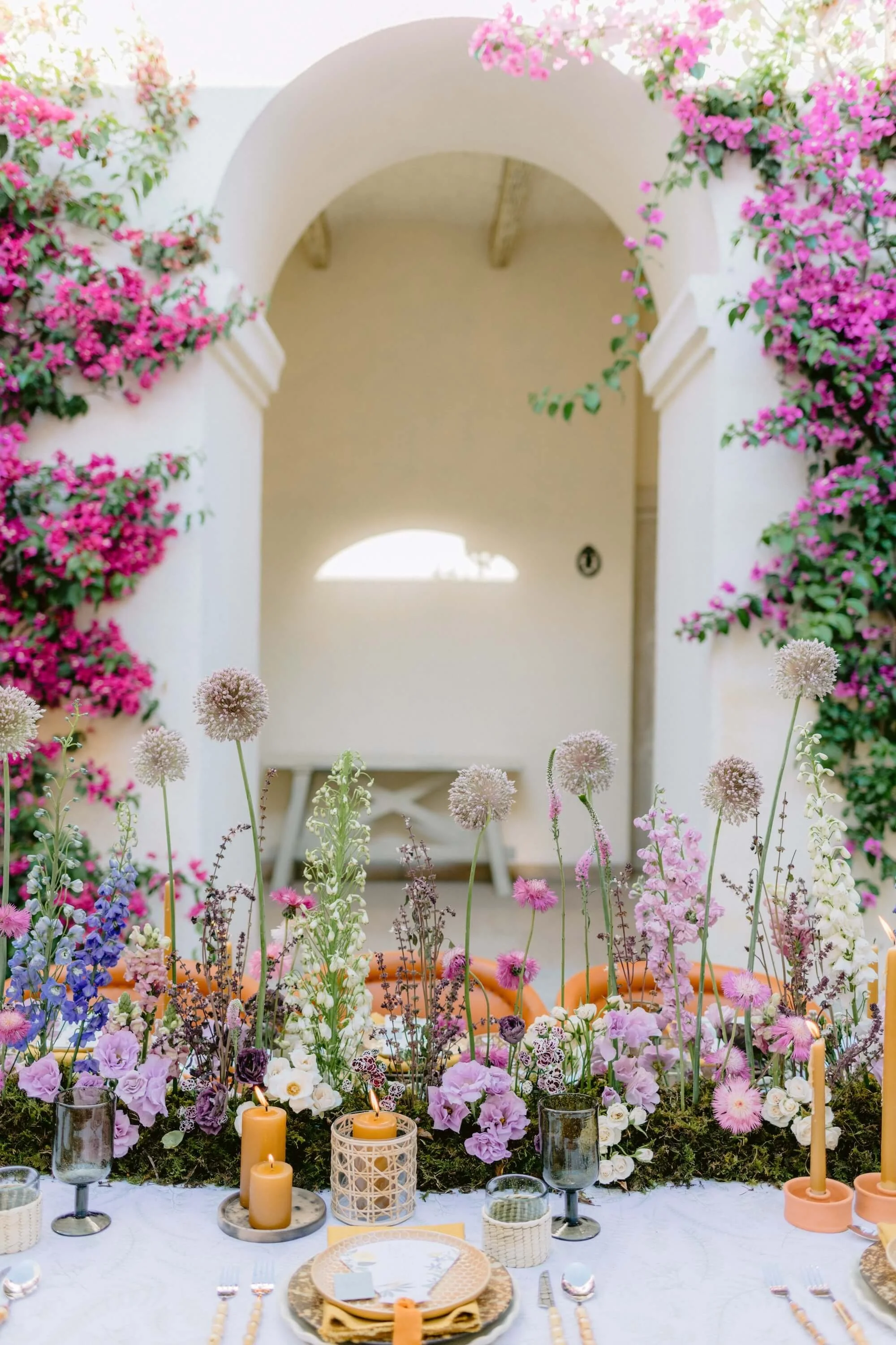 bride raising bouquet surrounded by soft floral installations and candles