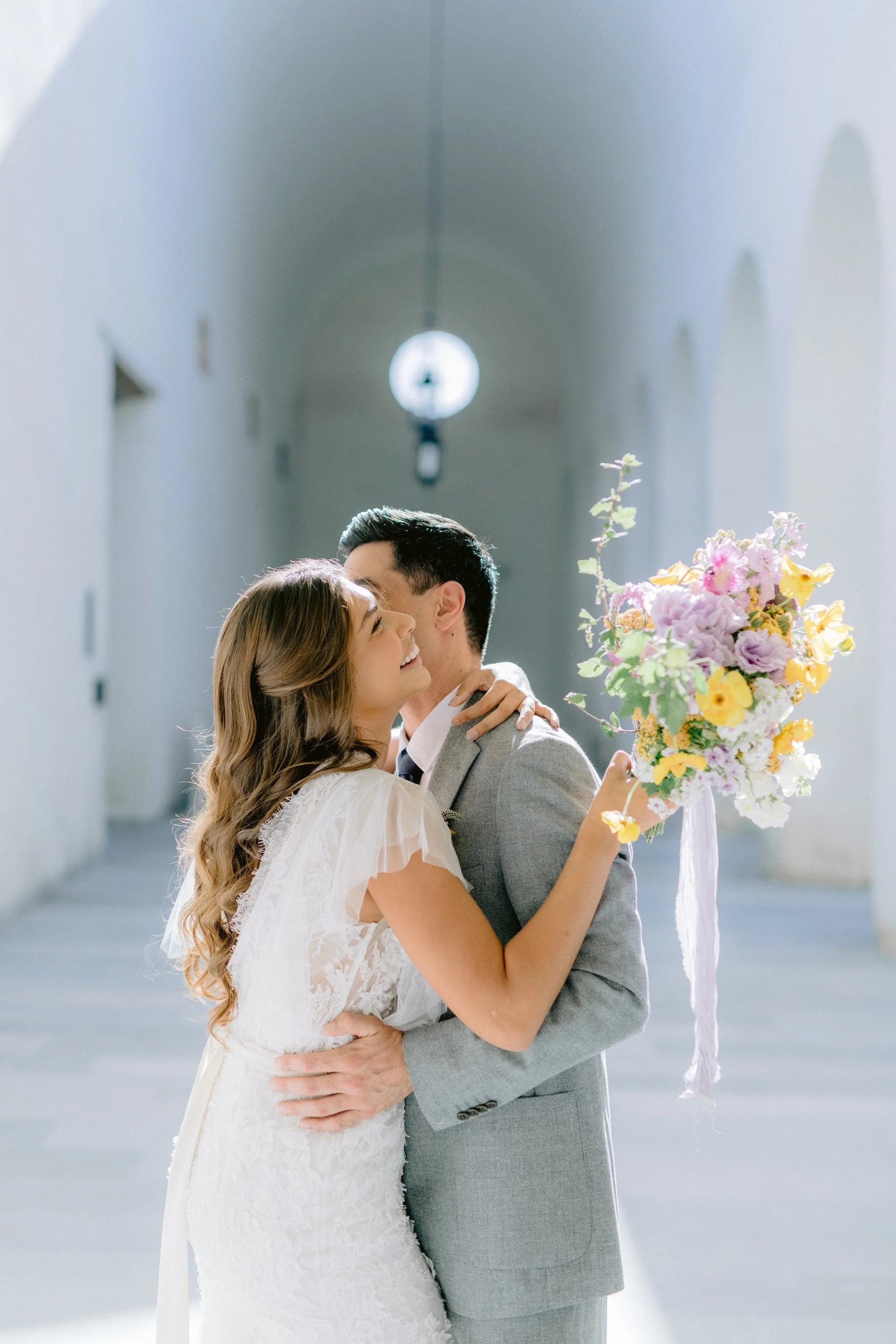 contemporary bride and groom near pool with bold yellow floral arrangement