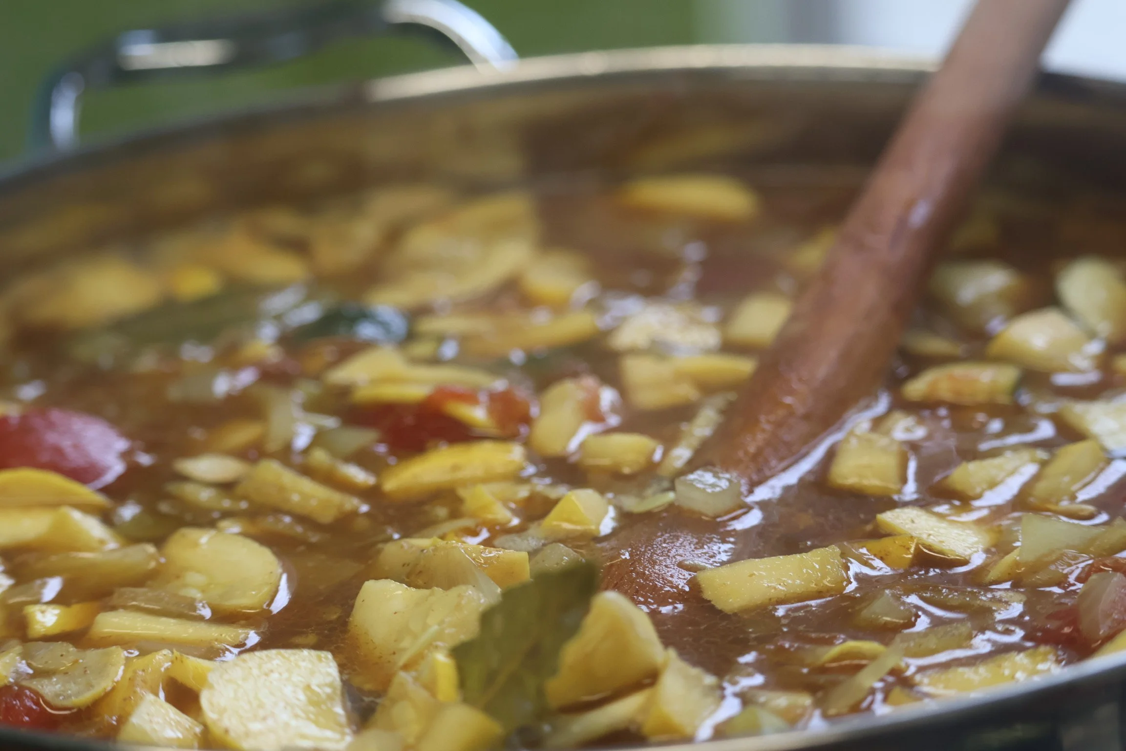 Potatoes cooking in a brown sauce with a cinnamon stick inside.