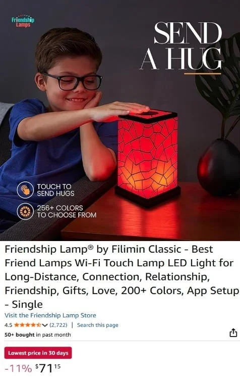 A young boy with glasses smiling and touching a red colorful friendship lamp on a table, with the words 'Send a Hug' and 'Touch to Send Hugs' displayed, along with additional product information.
