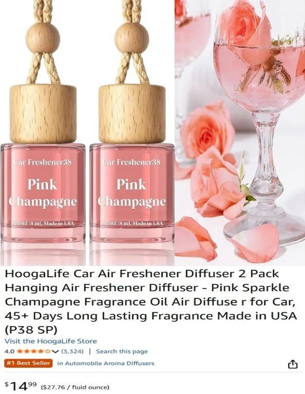 Two pink car air freshener bottles labeled 'Pink Champagne' with wooden hanging tops, placed next to a glass of pink champagne and pink roses.