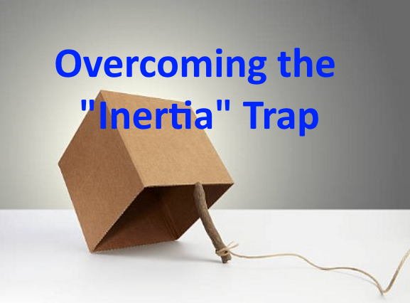 Illustration of a wooden mouse trap with a cardboard box and a rope, representing overcoming the ' inertia' trap, with blue text reading 'Overcoming the "Inertia" Trap'.