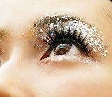 Close-up of a person's eye with glitter eyeshadow and decorative rhinestones around the eyelid.