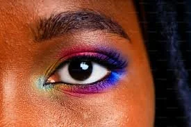 Close-up of a person's eye with colorful rainbow eyeshadow and eyeliner