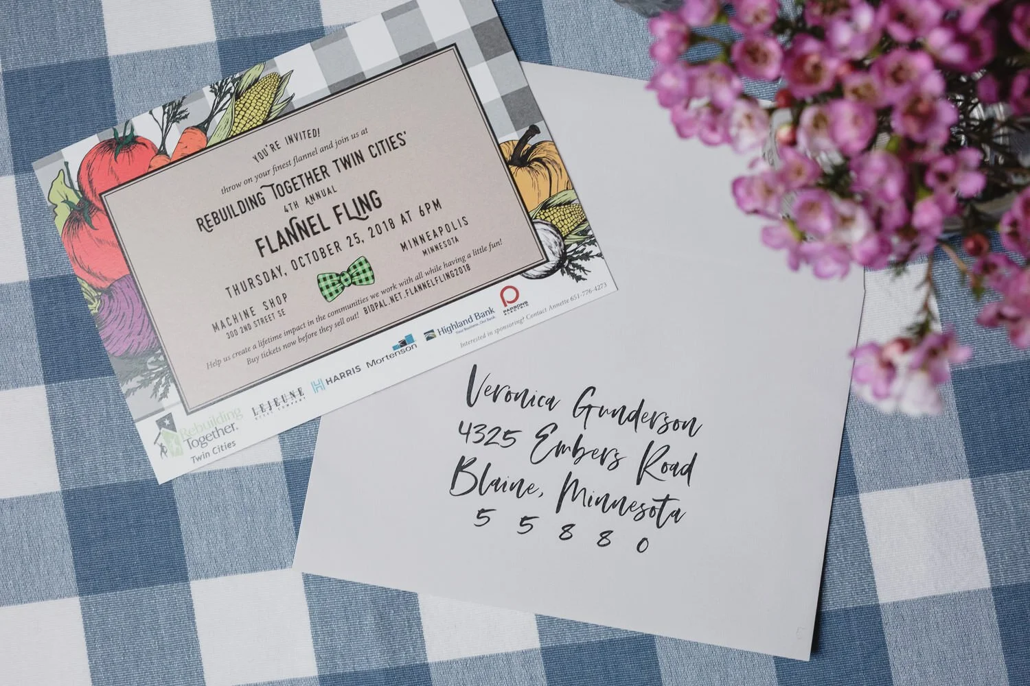 Americana themed invitation on blue plaid tablecloth with pink flowers