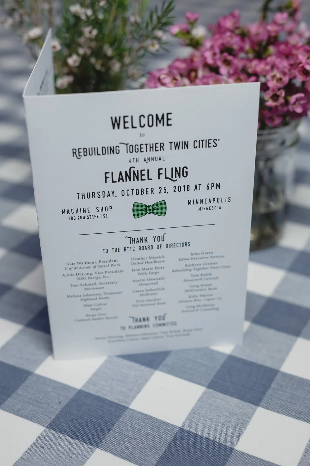 paper welcome sign for Americana farm themed event on blue plaid tablecloth with pink flowers