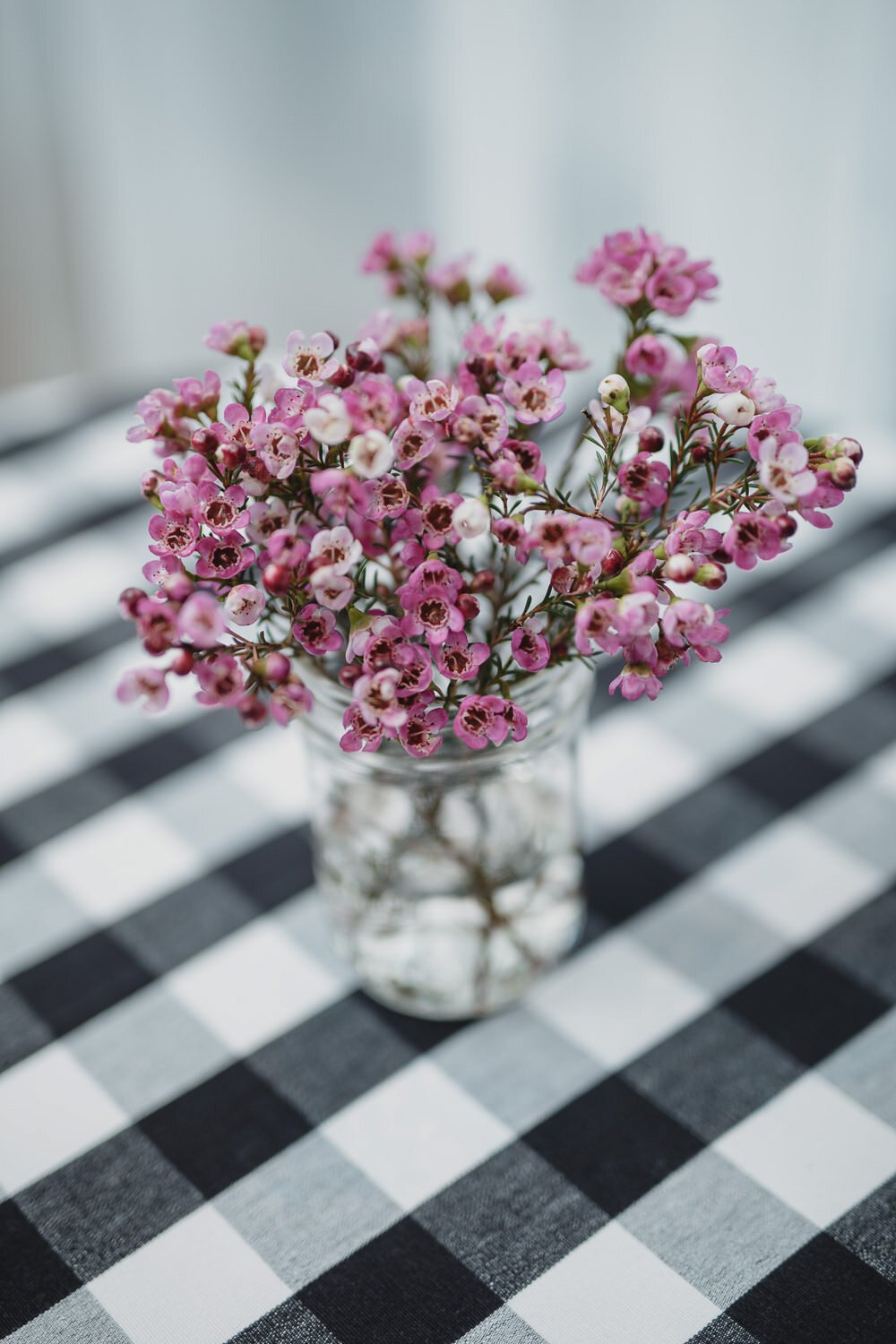 pink flowers in mason jar on black plaid tablecloth for Americana farm themed event