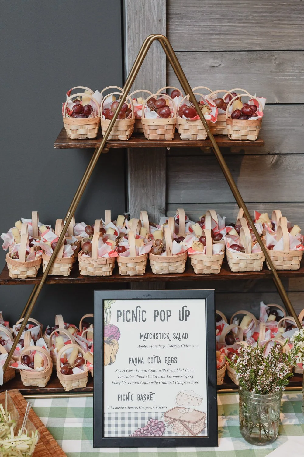 display of mini picnic baskets with cheese and fruit on triangle brass and wood shelves