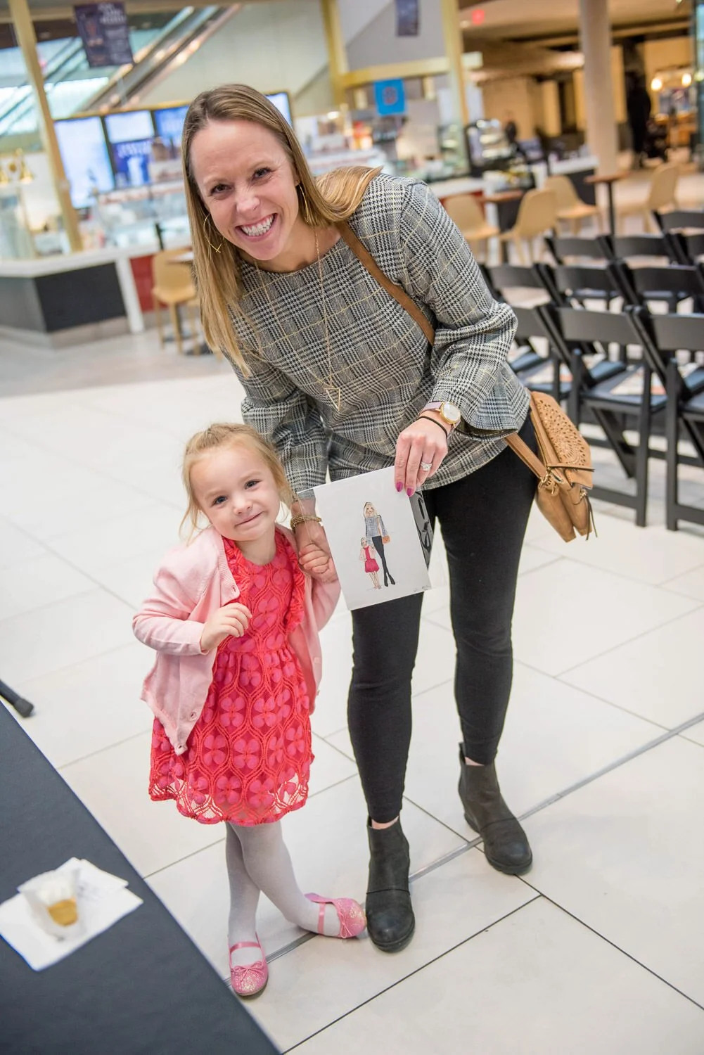 mom and daughter hold drawing of themselves at British inspired fashion event