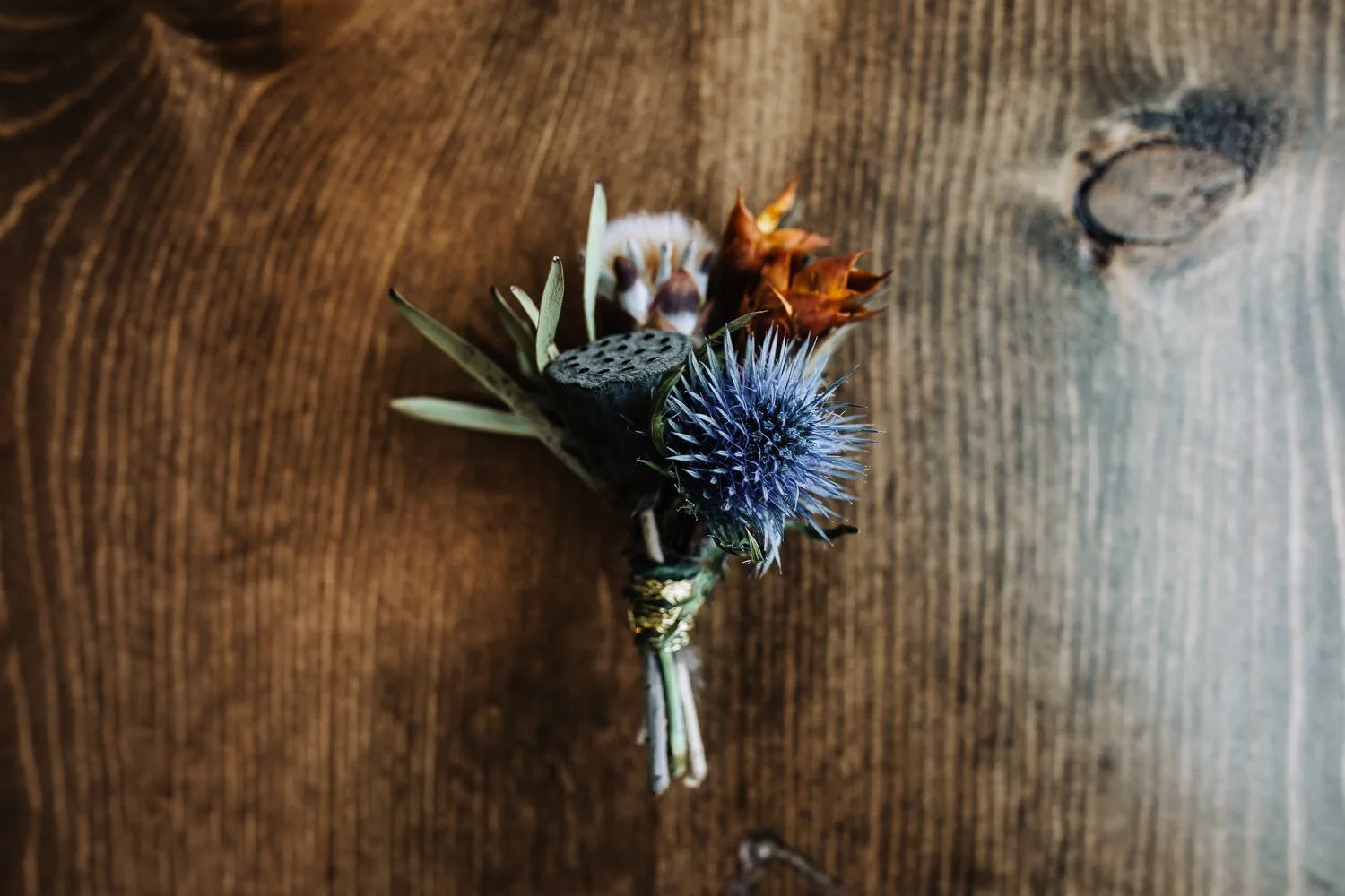 modern groom’s boutonniere with periwinkle spiky flower and burnt orange dried flower