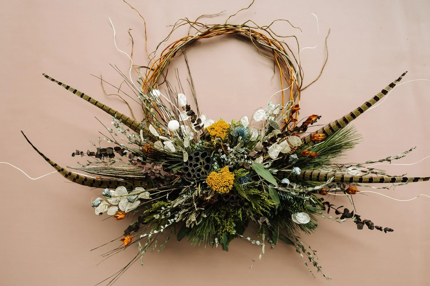 hoop bouquet of a variety of dried flowers, greens and striped feathers