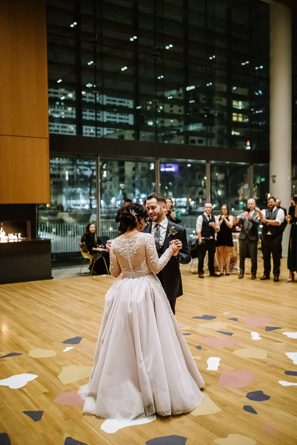 bride in long sleeved lace gown dancing first dance with groom atop modern geometric patterned floor decals