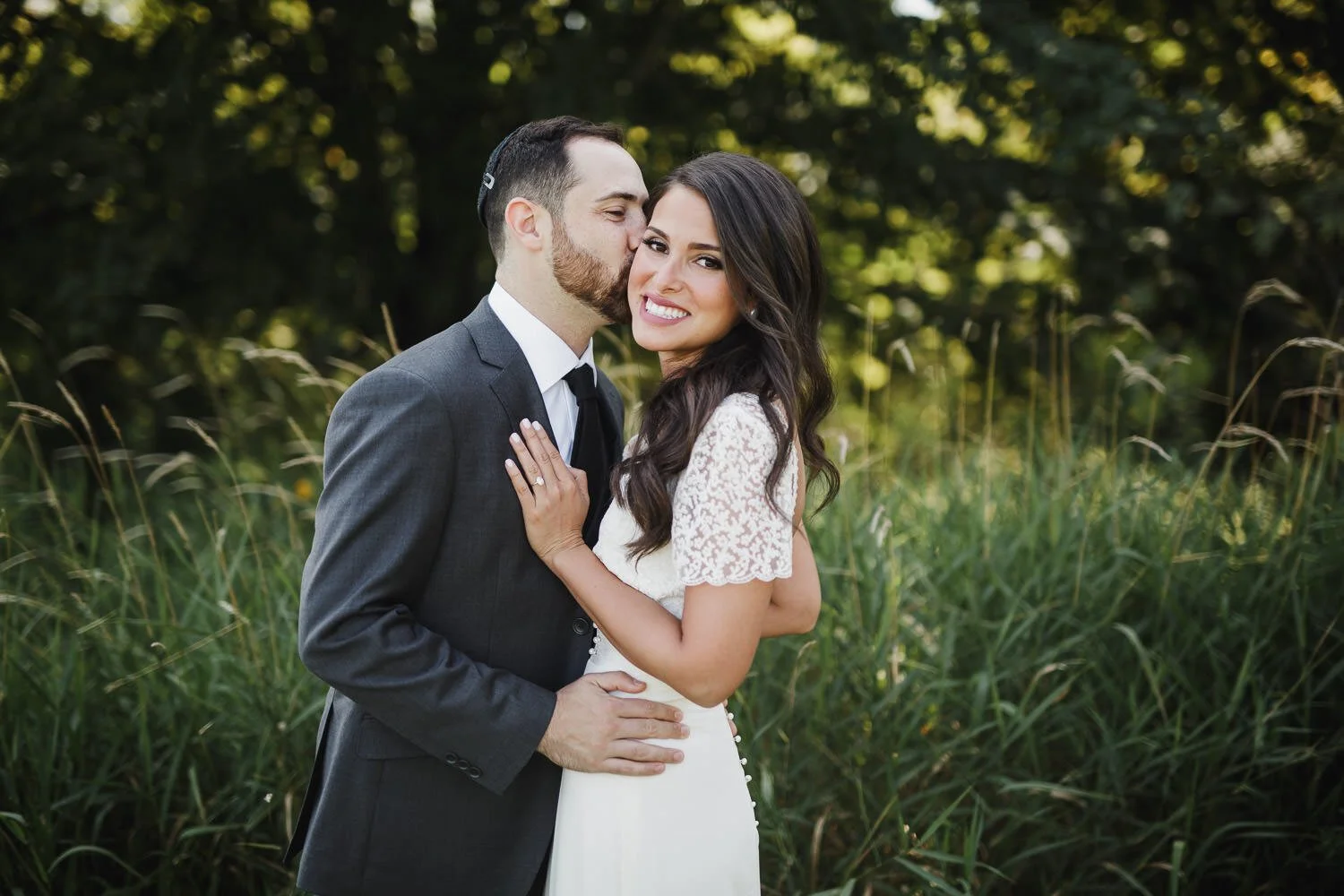 groom kissing bride on cheek and bride laughing