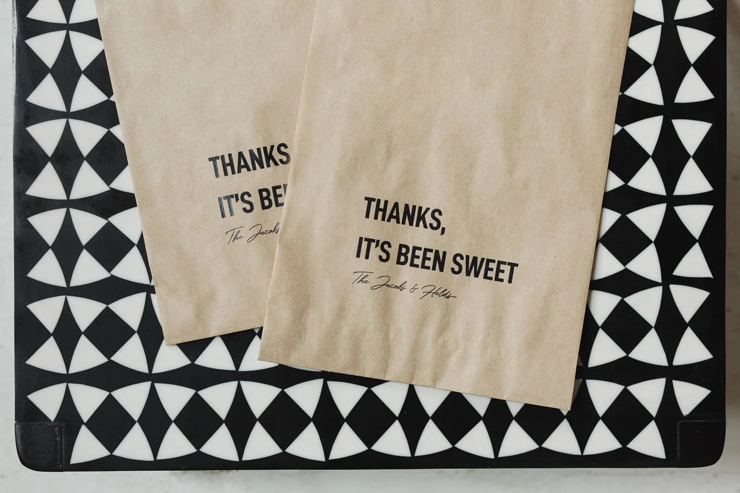 natural brown napkins with “thanks it’s been sweet” on black and white geometric design table.