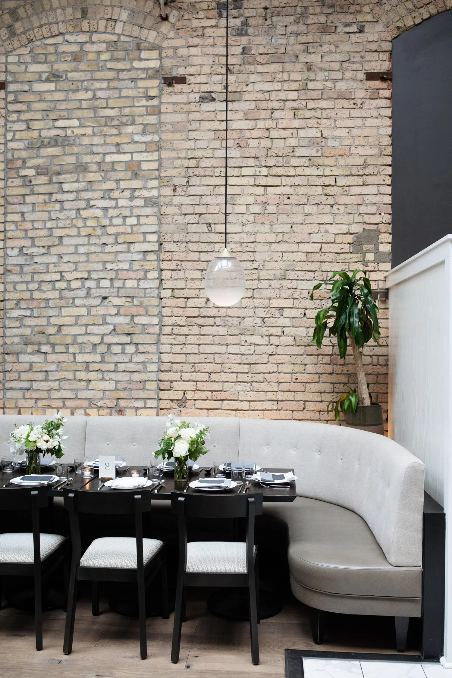 Black long tables and curved modern seating with white tableware. in front of old brick walls. White daisies are placed perfectly. Minneapolis rehearsal dinner, Spoon and Stable restaurant, Designed by Rocket Science Events.