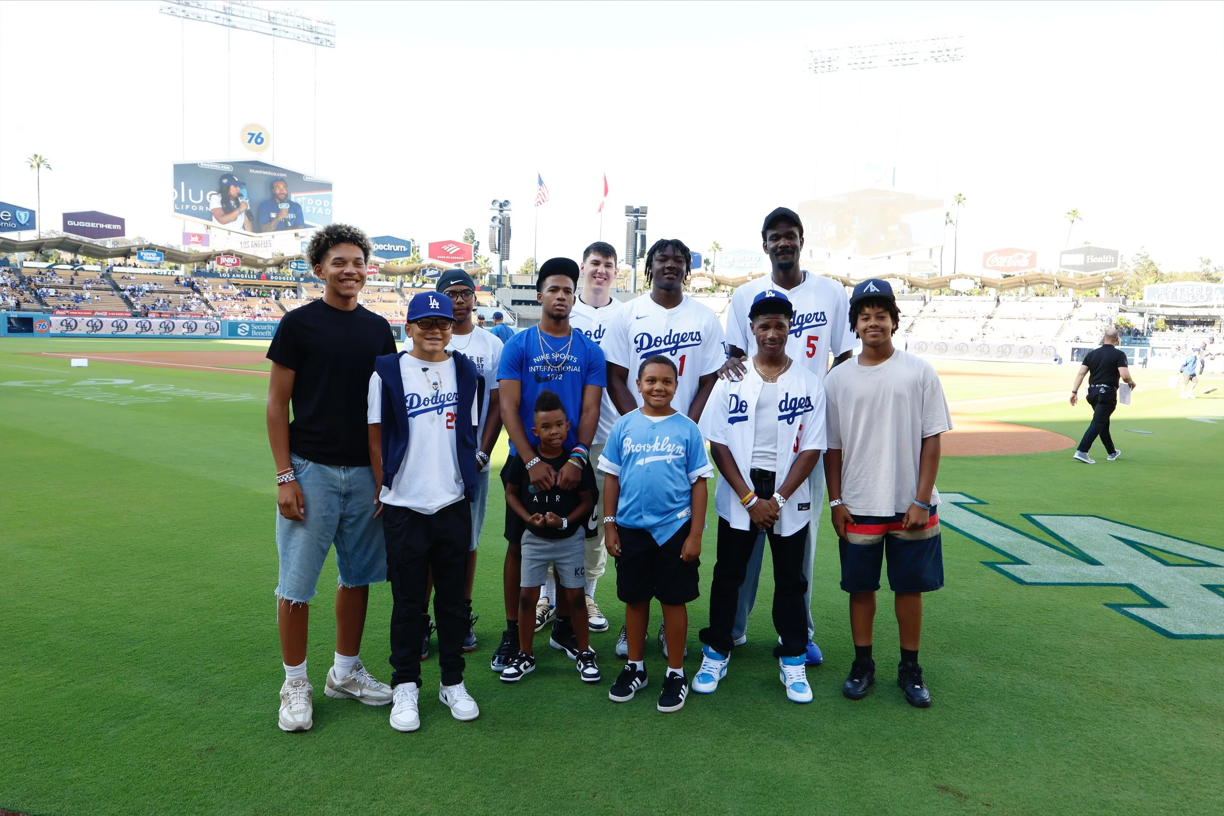 Group of children and two baseball players standing on a baseball field, smiling for a photo.