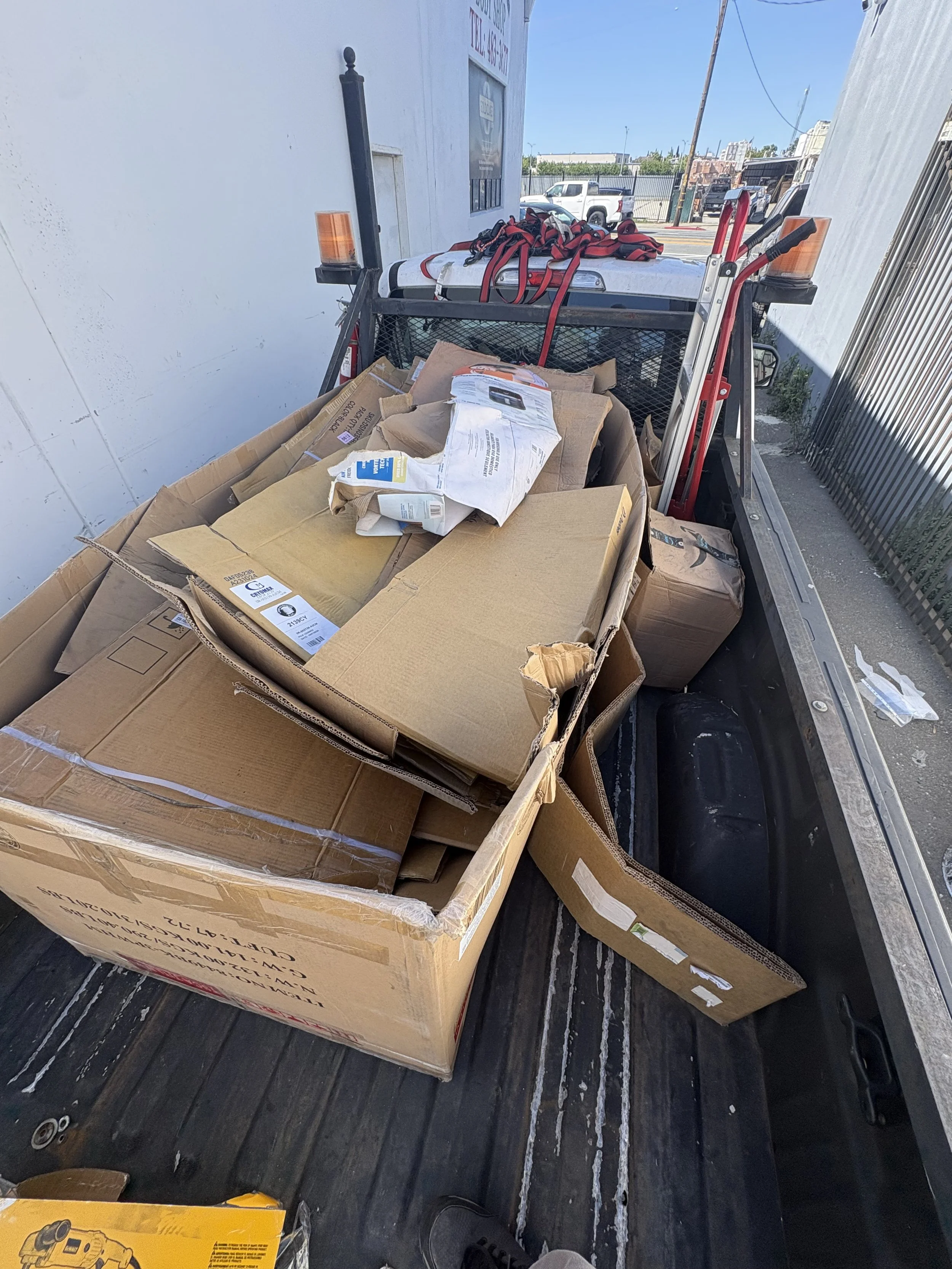 A flatbed truck with cardboard boxes, packages, and various items loaded onto it.