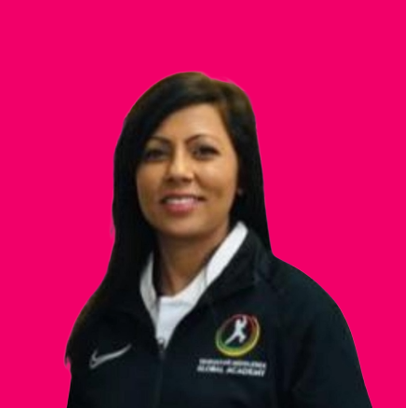 A woman with shoulder length dark hair wearing a black jacket with the Texas flag on the logo and a Nike swoosh, standing against a bright pink background.