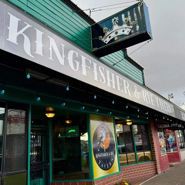 Exterior view of Kingfisher & Rye Tavern with a prominent signboard displaying the tavern's name and a smaller sign with a kingfisher bird illustration.