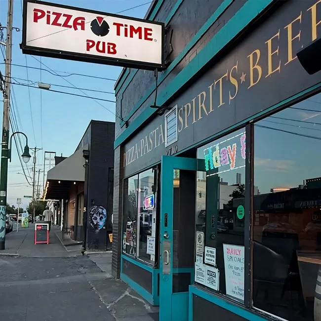 Street view of a restaurant and pub with signs advertising pizza, pasta, spirits, beer, and daily specials, and a Pizza Time Pub sign overhead.