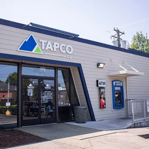 Exterior view of a TAPCO CU credit union branch with an ATM and a storefront with glass doors.