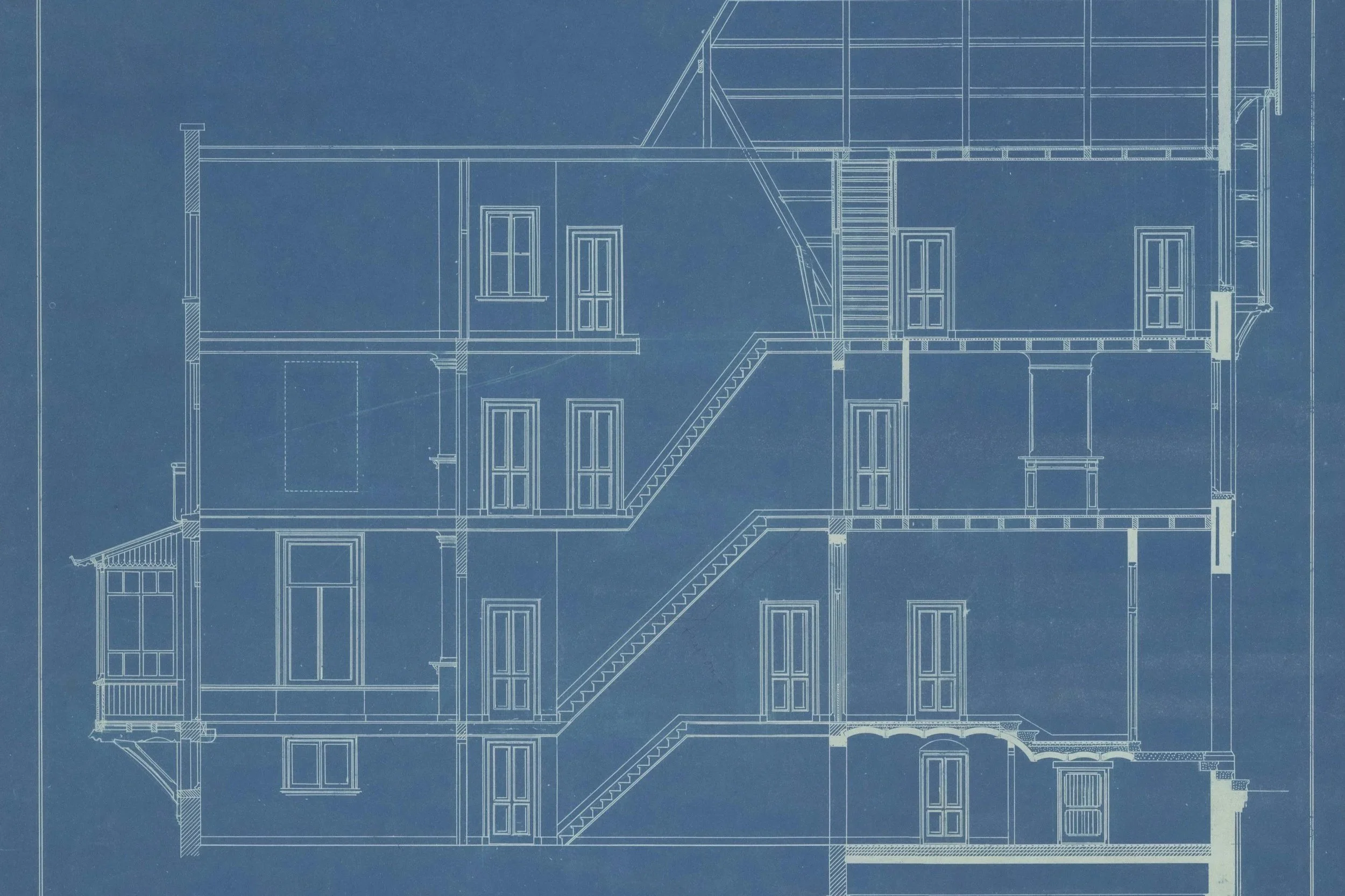Blueprint drawing of a multi-story house showing interior layout, stairs, and exterior windows and doors.