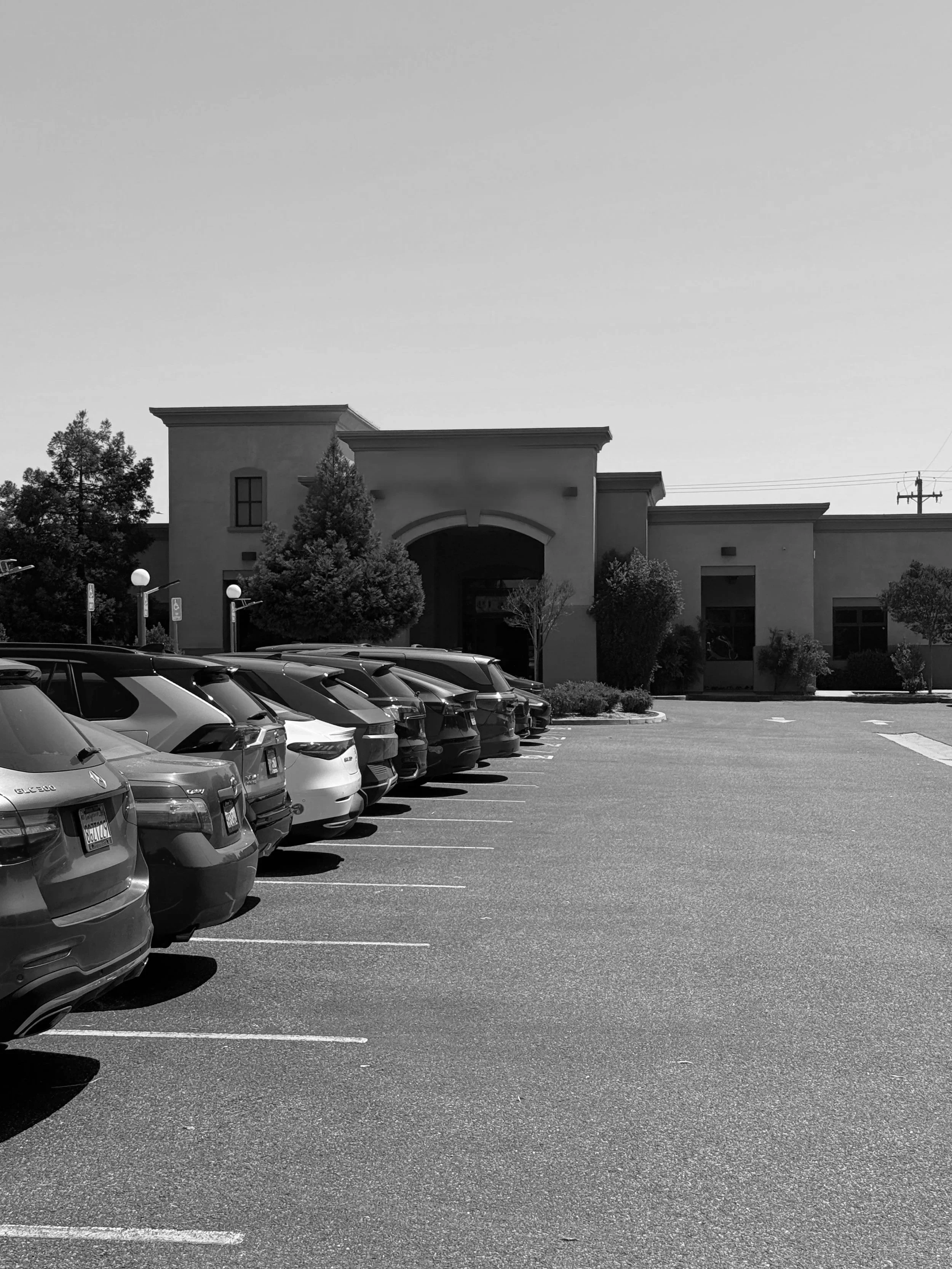 A parking lot with several parked cars and a building in the background.