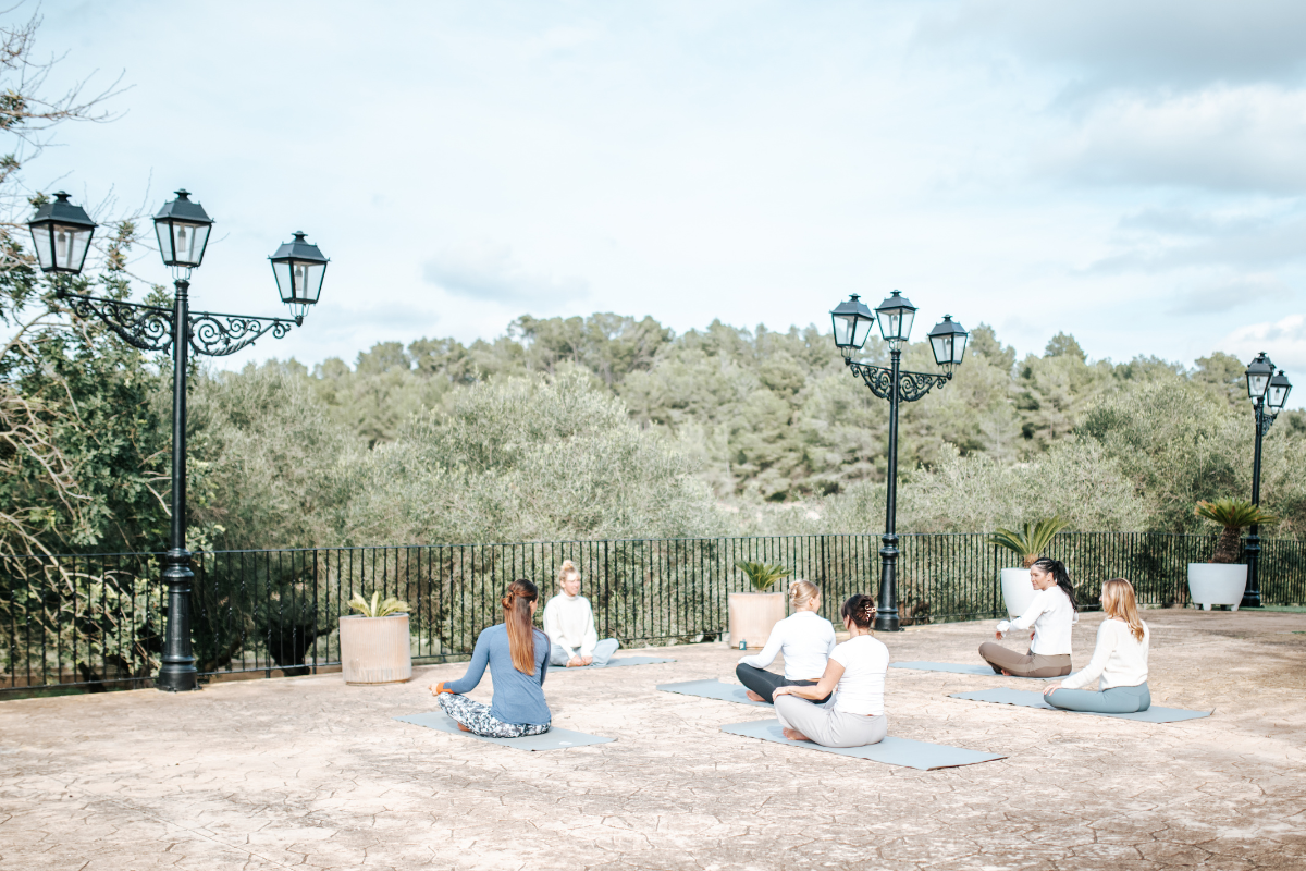 Menschen, die Yoga auf einer Terrasse im Freien beim Sonnenaufgang oder Sonnenuntergang praktizieren.