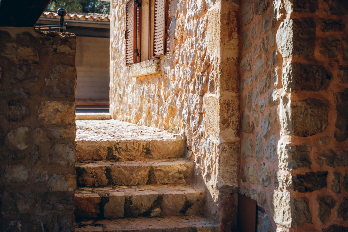 Steinerne Treppe an einer Steinmauer am Eingang eines Gebäudes mit geschlossenem Holzfensterläden.