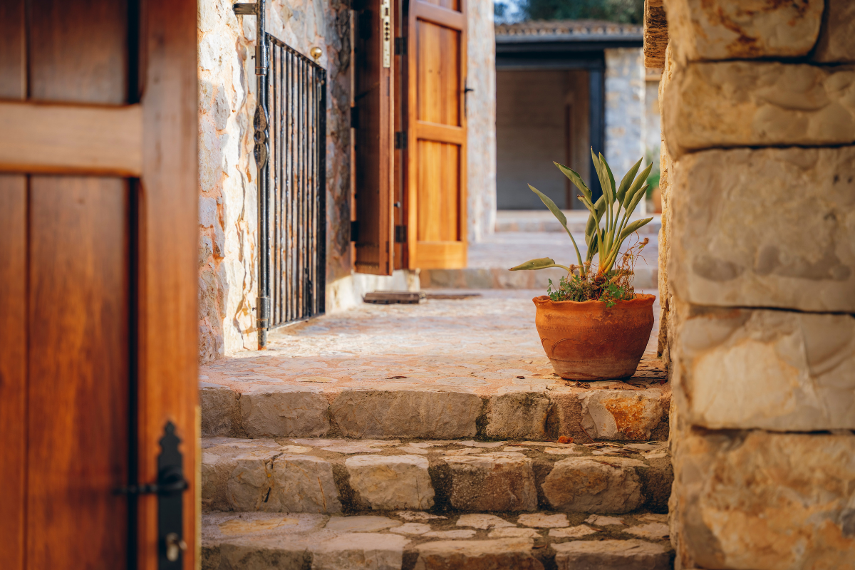 Steinverzierte Treppe mit Blumentopf vor einem Holz- und Steingebäude