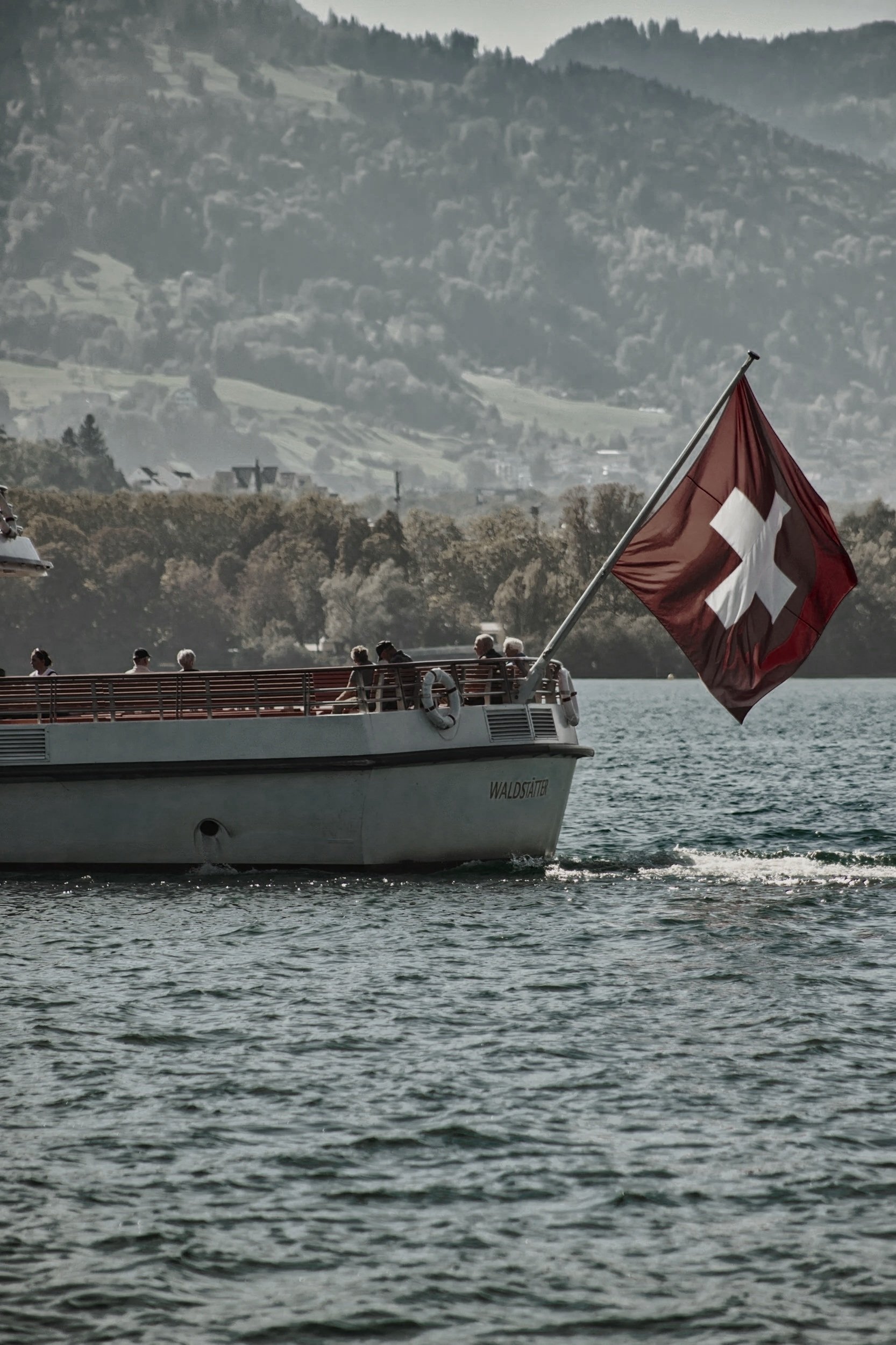 Un bateau naviguant sur un lac avec le drapeau suisse déployé