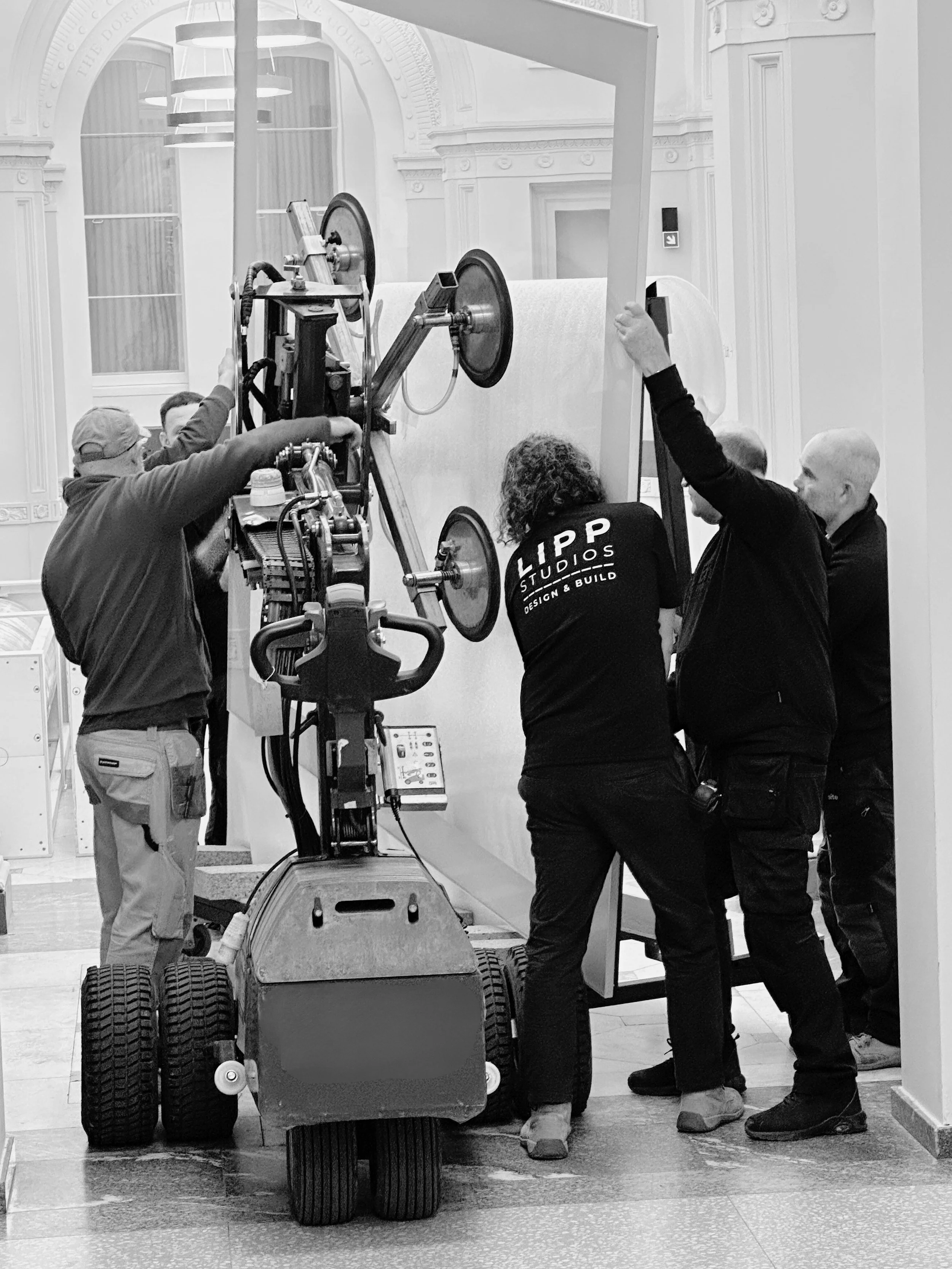 Crew members working with film or camera equipment indoors, likely setting up or adjusting for a shoot or project.