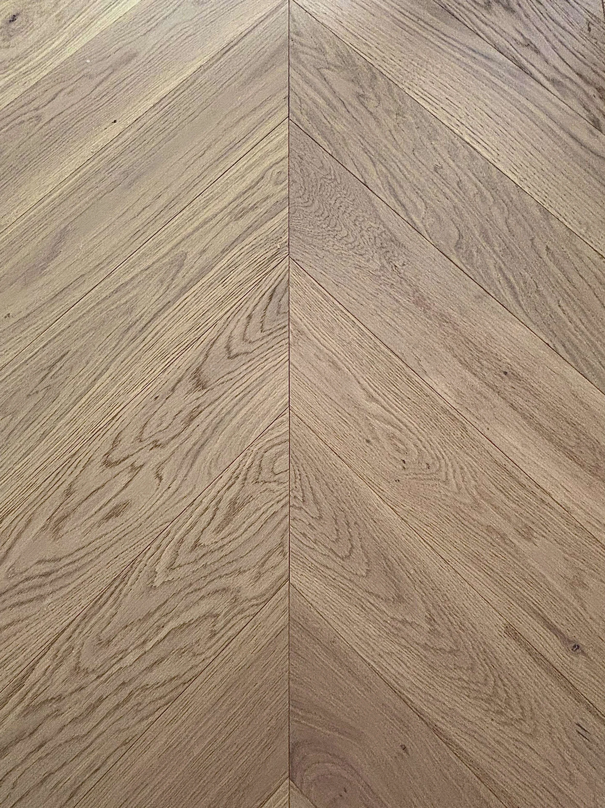 Close-up of a wooden floor arranged in a herringbone pattern.